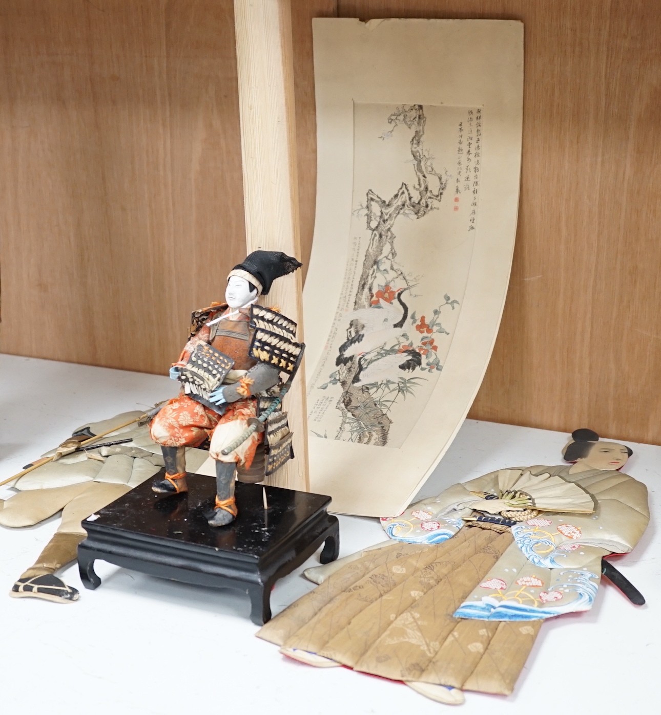 A Japanese seated Samurai figure on stand, two appliquéd fabric figures and a Chinese print, tallest figure 48cms high